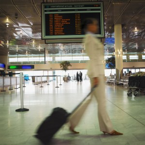 Side view of businesswoman walking in airport and carrying luggage